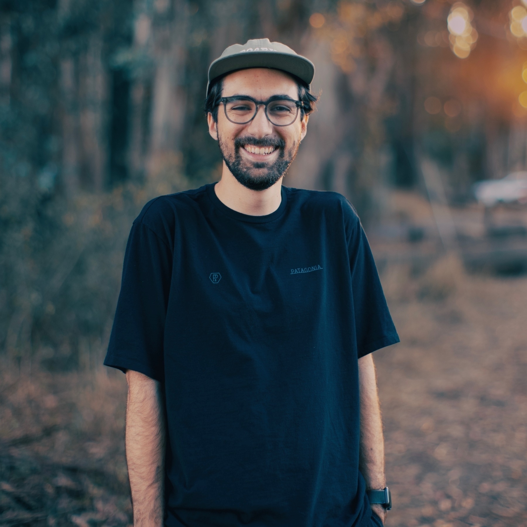 Me, smiling in front of some trees with my hands in my pockets.