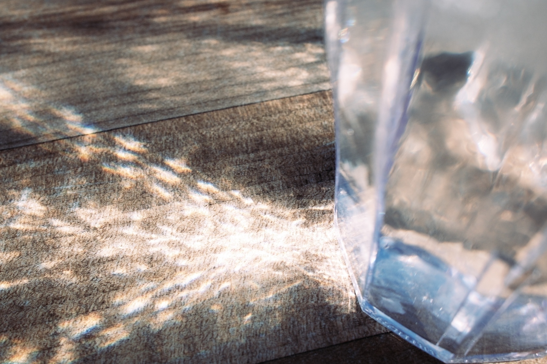 Light refracting through a water cup and lighting up the table next to it.